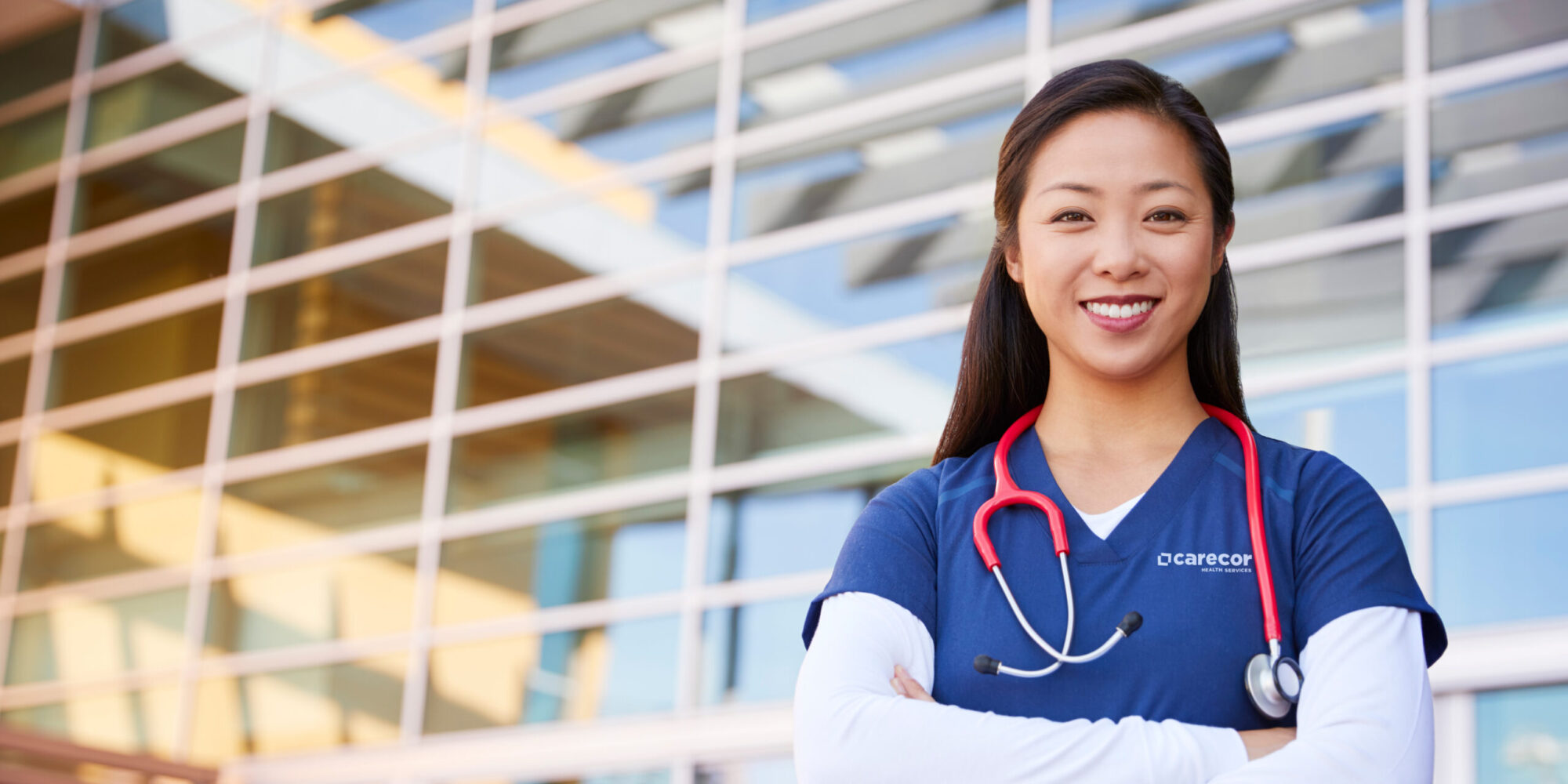 Smiling Asian female healthcare worker with arms crossed